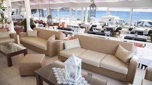 Een ruim buitgedeelte met meerdere banken en tafels, met uitzicht op een strand en de zee.