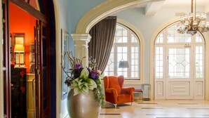 A lobby with a large vase of flowers, an orange armchair, and a chandelier. - INATEL Palace S Pedro Do Sul (Sao Pedro do Sul)
