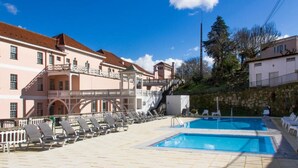 A pool area with lounge chairs, a staircase, and a building with balconies. - INATEL Palace S Pedro Do Sul (Sao Pedro do Sul)