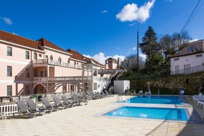 Piscine extérieure en saison, parasols, chaises longues