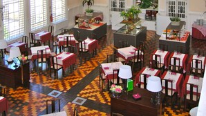 A spacious dining area with multiple tables and chairs, large windows, and a decorative ceiling. - INATEL Palace S Pedro Do Sul (Sao Pedro do Sul)