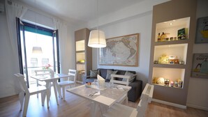 A modern dining area with a white table and chairs, a map on the wall, and shelves with food items. - B&B Medinblu Via Miraglia (Reggio Calabria)