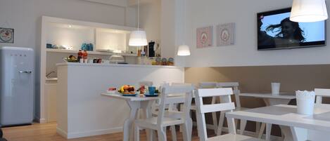 Una cocina moderna con armarios blancos y un comedor con sillas y mesas también blancas.