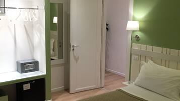 A bedroom with a bed, a bedside table, a mirror, a wardrobe, and a lamp.