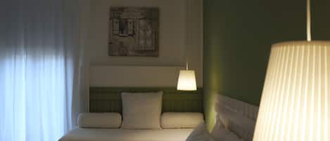 A hotel room with a bed, a headboard, a wall-mounted artwork, and a hanging lamp.
