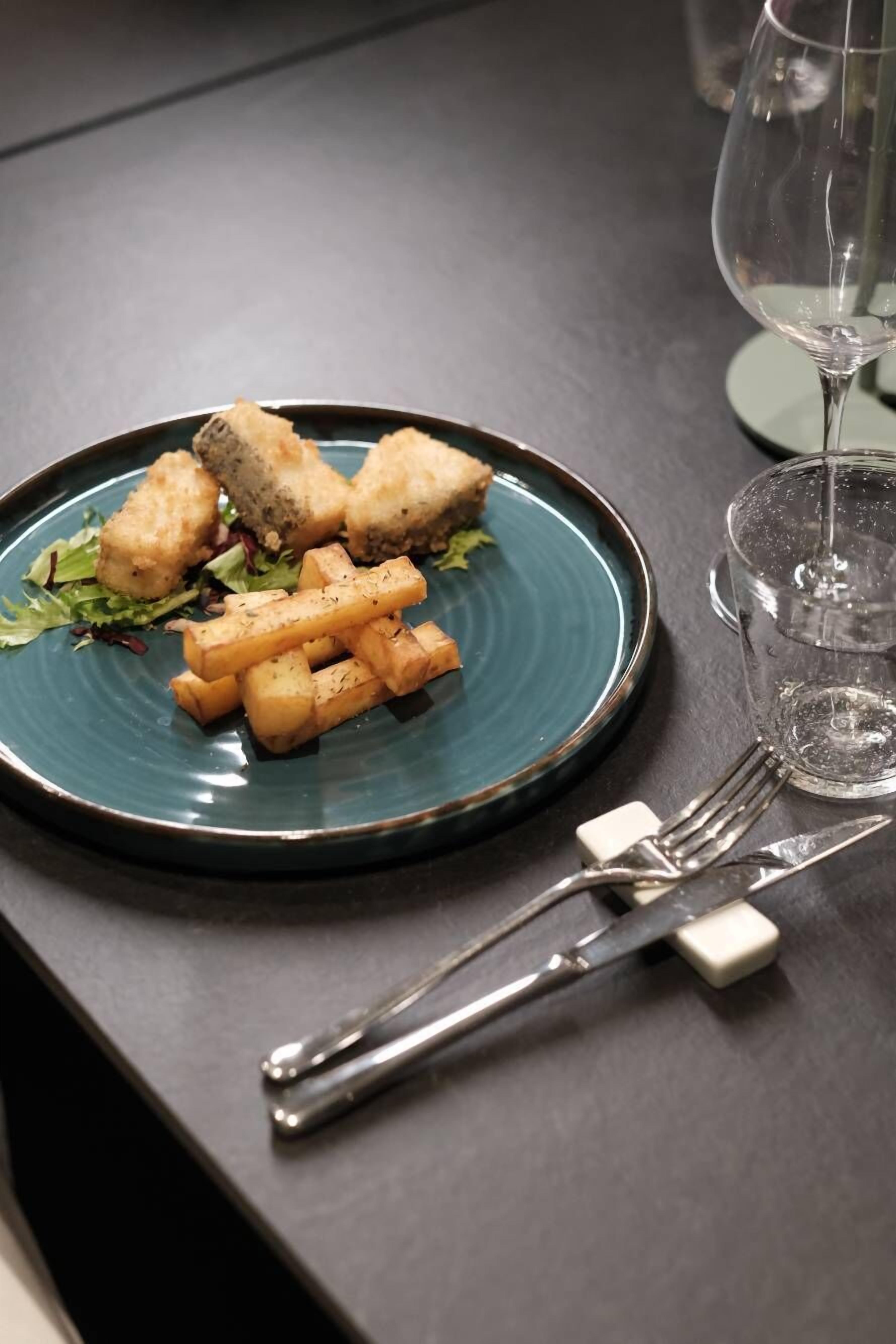 Un plato de comida con batatas fritas y una copa de vino sobre una mesa.