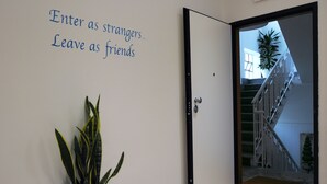 A hallway with a door that has a sign reading "Enter as strangers, Leave as friends." A potted plant is visible to the left of the door. - B&B Medinblu Via Miraglia (Reggio Calabria)