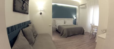 Quarto de hotel moderno com cama, sofá, escrivaninha e cadeira.