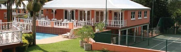 A two-story building with a swimming pool, outdoor seating, and a tennis court. - Sica's Guest House (Durban)