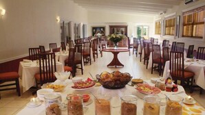 Un espace repas avec plusieurs tables dressées pour les repas, des chaises et divers aliments.