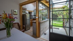 Une cuisine équipée d’un réfrigérateur, avec des poutres en bois et une fenêtre donnant sur un jardin.