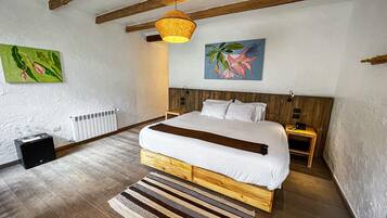 Un dormitorio con una cama de madera, una lámpara colgante, un radiador y un cuadro en la pared.