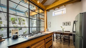 Une cuisine dotée d’une grande fenêtre, de poutres en bois, d’une cuisinière à gaz et d’un réfrigérateur.