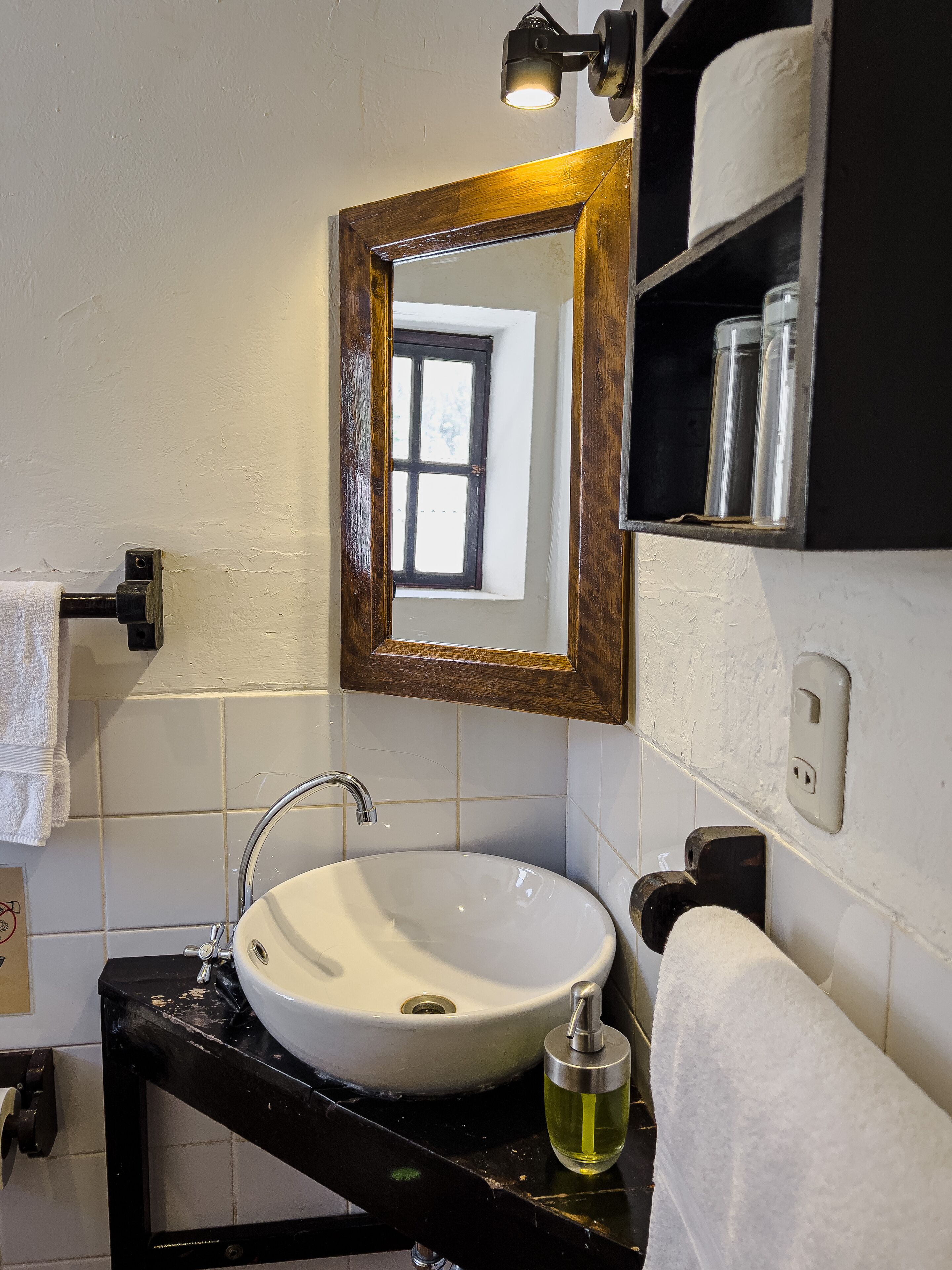 A bathroom with a white sink, black countertop, and a mirror with a wooden frame.