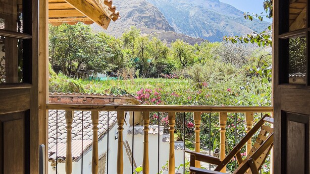 Un balcon en bois offrant une vue sur un paysage montagneux.