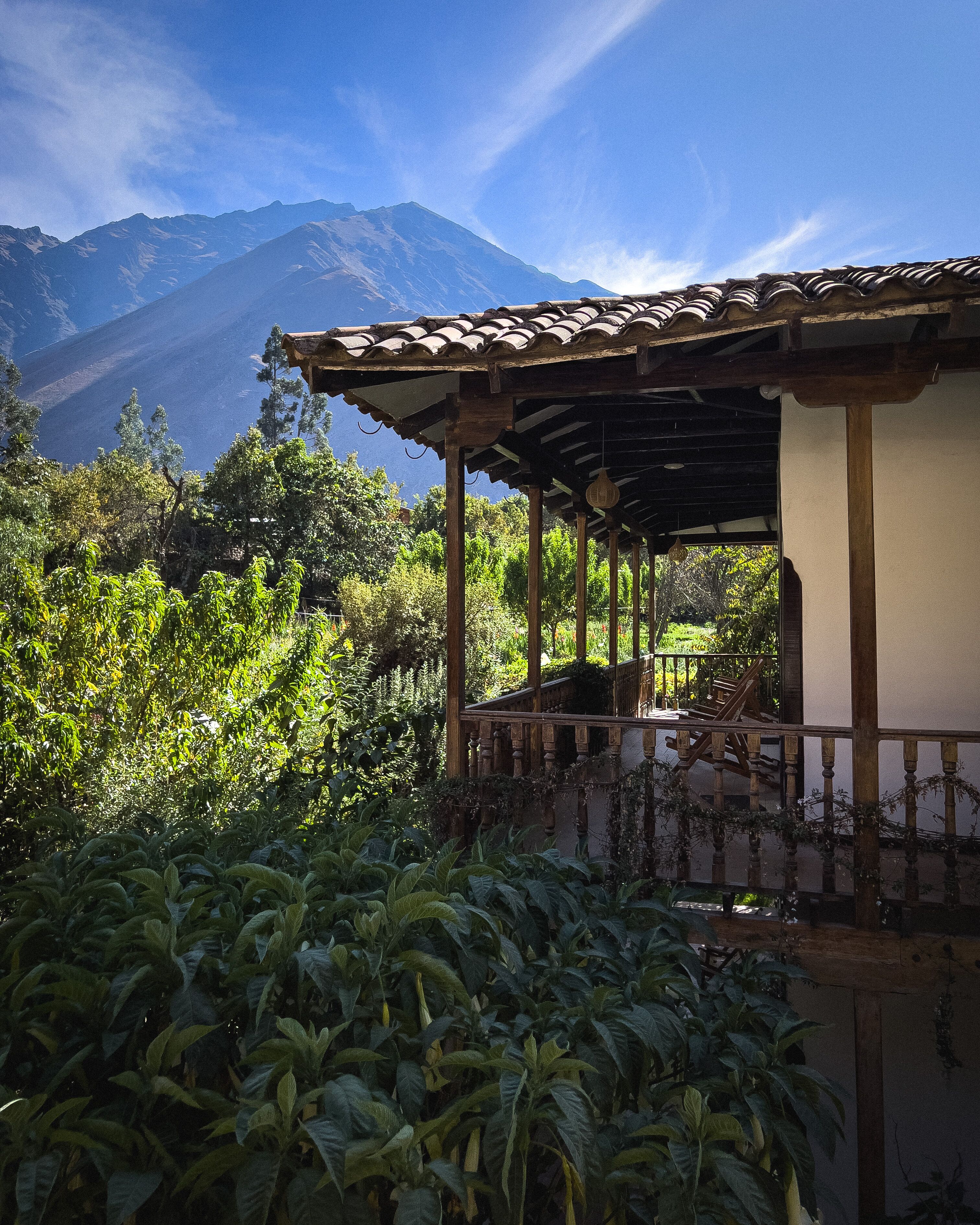 Un espacio al aire libre cubierto con una estructura de madera, rodeado de abundante vegetación y un paisaje montañoso.