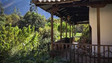 Un espacio al aire libre cubierto con una estructura de madera, rodeado de abundante vegetación y un paisaje montañoso.