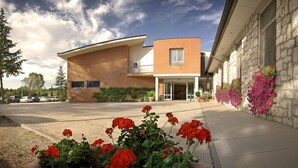 A modern building with a brick facade, a covered entrance, and a parking lot. - I Girasoli (Lucignano)