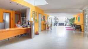 A bright reception area with a receptionist, a reception desk, potted plants, and a view of the lobby. - I Girasoli (Lucignano)