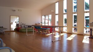 A spacious room with large windows, a wooden floor, and exercise equipment. - I Girasoli (Lucignano)