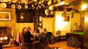 Ein gemütliches Restaurant mit Backsteinwand, Kamin und Billardtisch.