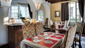 Ein Essbereich mit gedeckten Tischen für das Frühstück, inklusive eines Buffets mit verschiedenen Speisen und einer Kristallleuchter.
