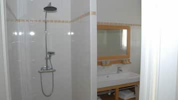 A bathroom with a shower, sink, and mirror.