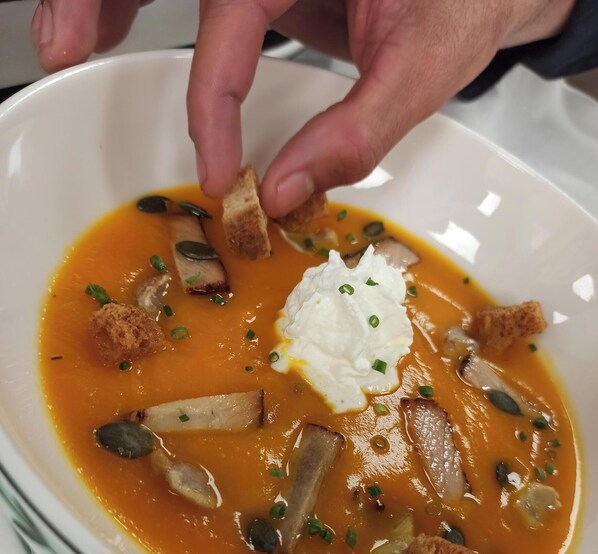 A bowl of soup with croutons, a dollop of cream, and green onions.
