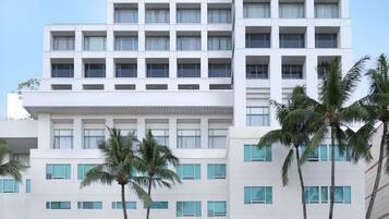 Un hôtel à plusieurs étages, doté d’une architecture moderne, avec une entrée principale et un espace de stationnement situé à l’avant.