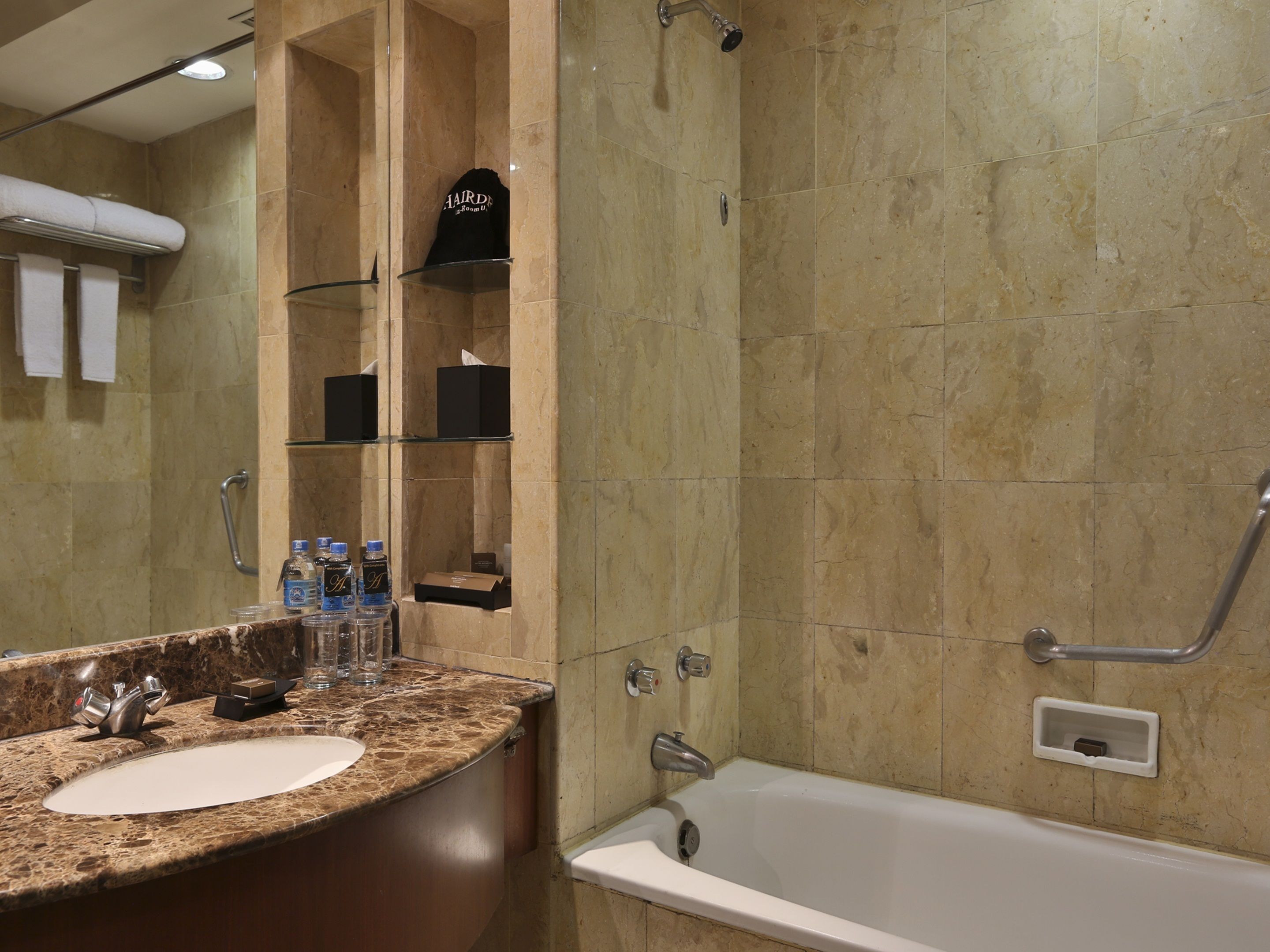A bathroom with a marble sink, a bathtub, and a glass shower enclosure.