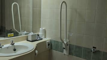 A bathroom with a sink, mirror, toilet, and a trash bin.