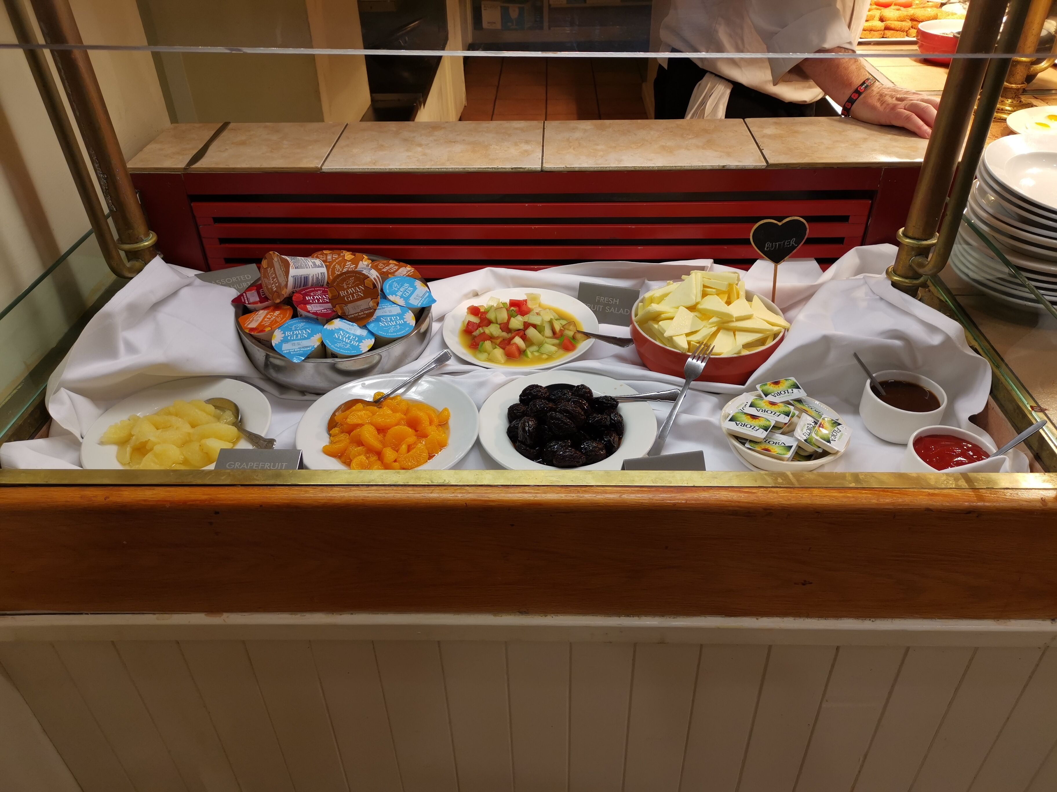 A buffet with various food items including fruits, desserts, and condiments.