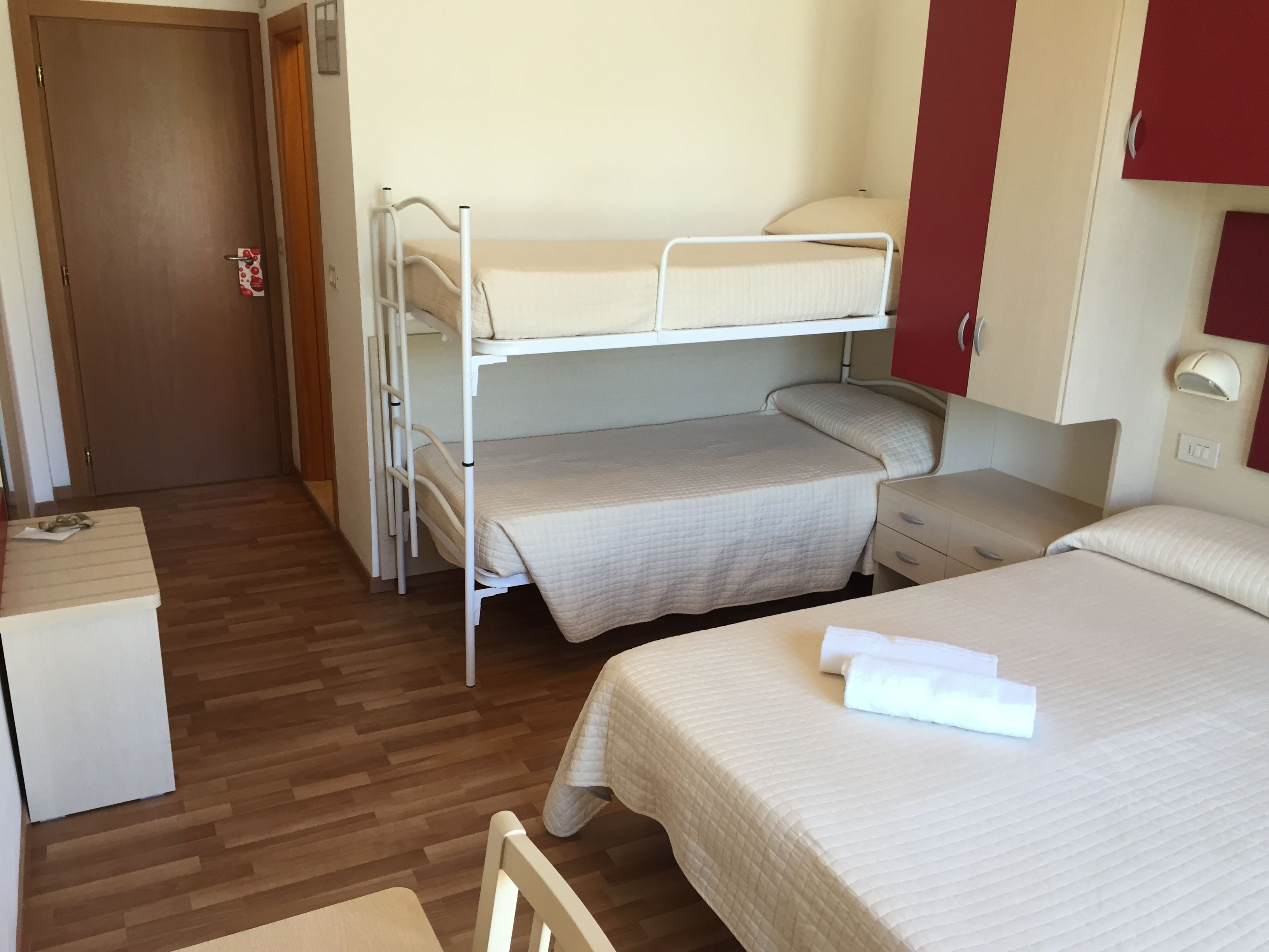 Quarto tipo dormitório com beliches, uma escrivaninha e mesa de cabeceira.