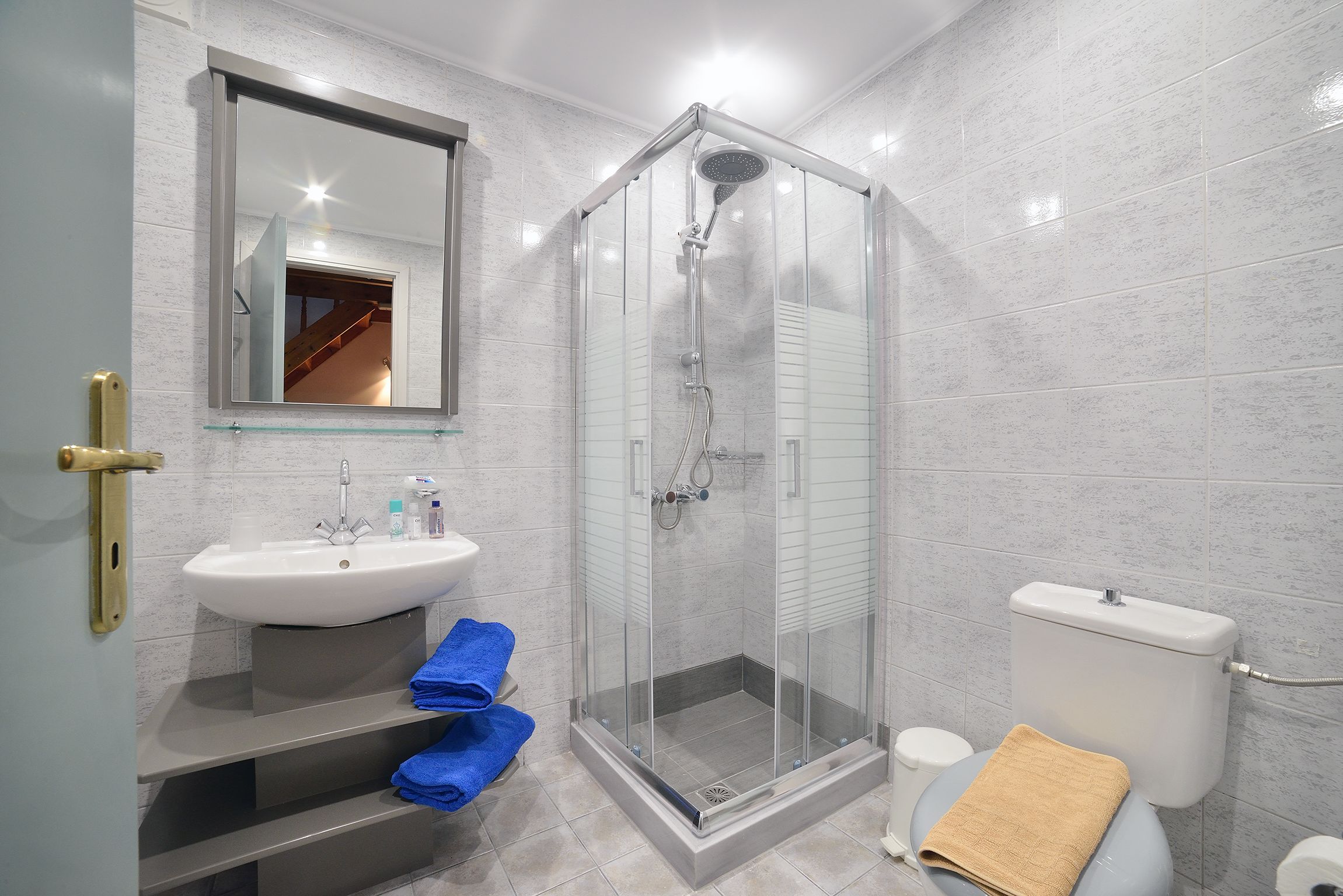 A modern bathroom with a glass-enclosed shower, a white sink, and a toilet.
