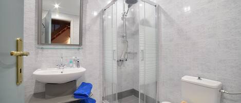 A modern bathroom with a glass-enclosed shower, a white sink, and a toilet.