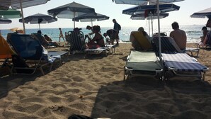 Una spiaggia con numerosi ombrelloni e lettini.