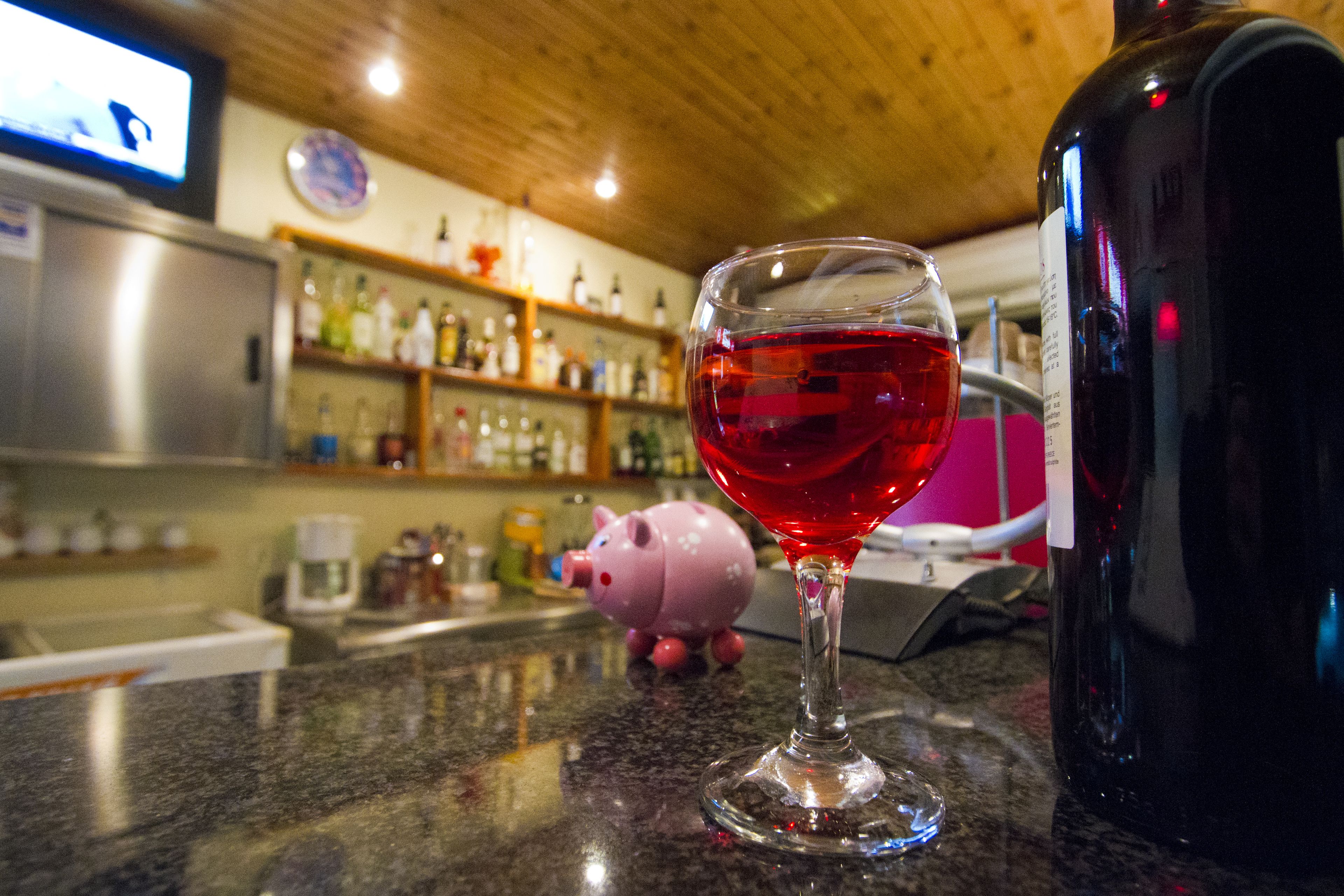 Un área de bar con una copa de vino, un cerdito alcancía y una pantalla de televisión.