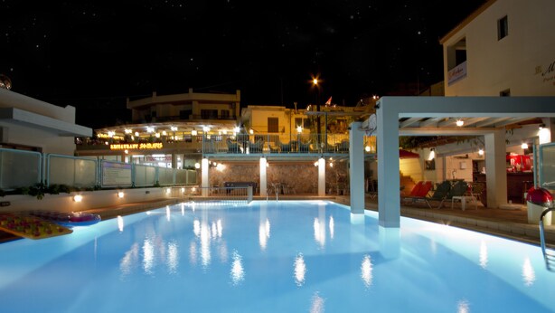 Una piscina con vista su un edificio con balcone e area salotto all'aperto.