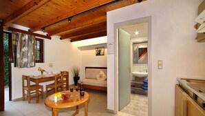 Una stanza accogliente con soffitto in legno, un'area pranzo con tavolo e sedie, un divano e una cucina con lavello e pensili.