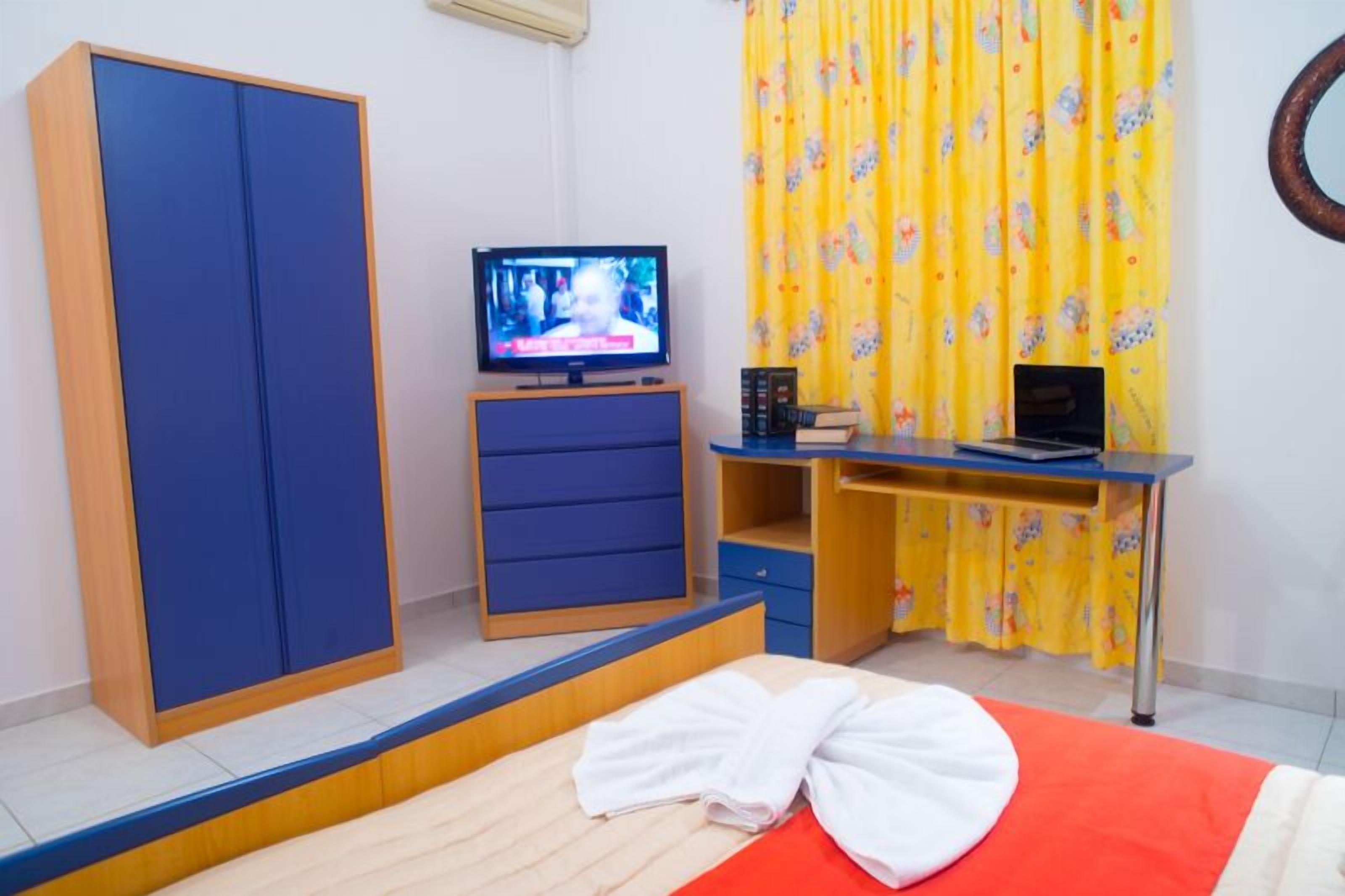 A room with a bed, a TV, a desk, and a wardrobe.