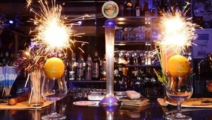 A bar with two glasses of orange juice, each topped with a sparkler. - Memories Apartments (Hersonissos)