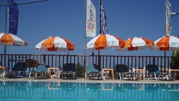 A swimming pool with lounge chairs and umbrellas. - Memories Apartments (Hersonissos)
