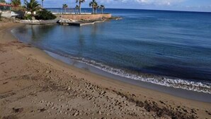 A beach with clear blue water, a sandy shore, and palm trees. - Memories Apartments (Hersonissos)