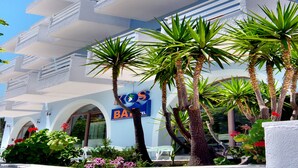 Un hotel con fachada azul y blanca, balcones y palmeras.
