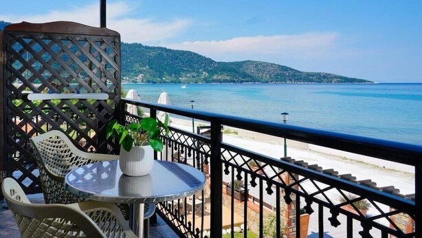 A balcony with a view of the sea, wicker chairs, a small table with a potted plant, and a railing. - Kamelia Hotel (SARONIC ISLANDS)