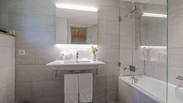A modern bathroom with a glass-enclosed shower, a white sink, and a mirror above it.