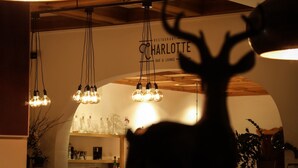 Interior de un restaurante con lámparas colgantes y un cartel que dice 'Charlotte Bar & Lounge'.