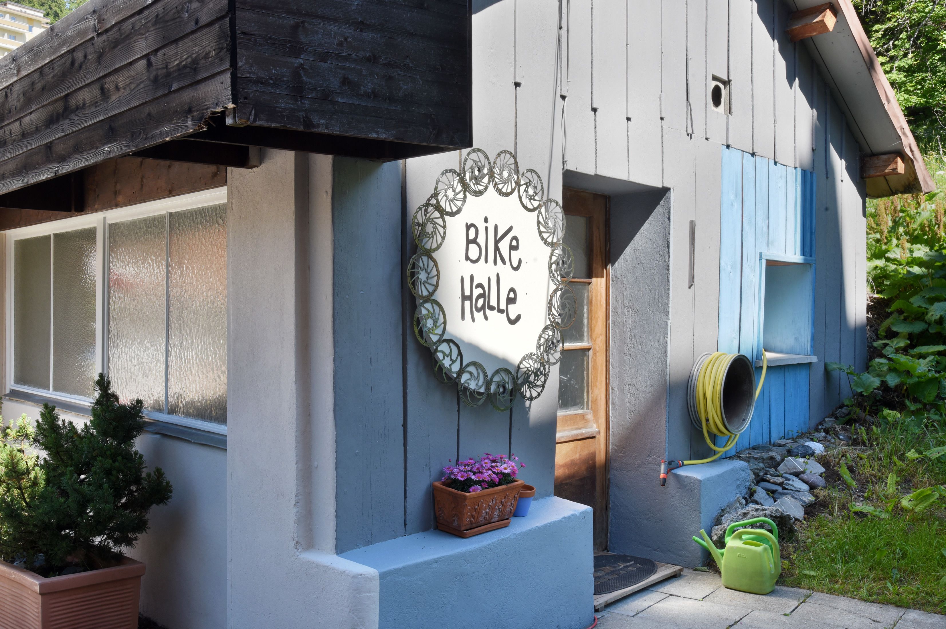 A building with a sign that reads "Bike Halle" and a small garden area with potted plants.