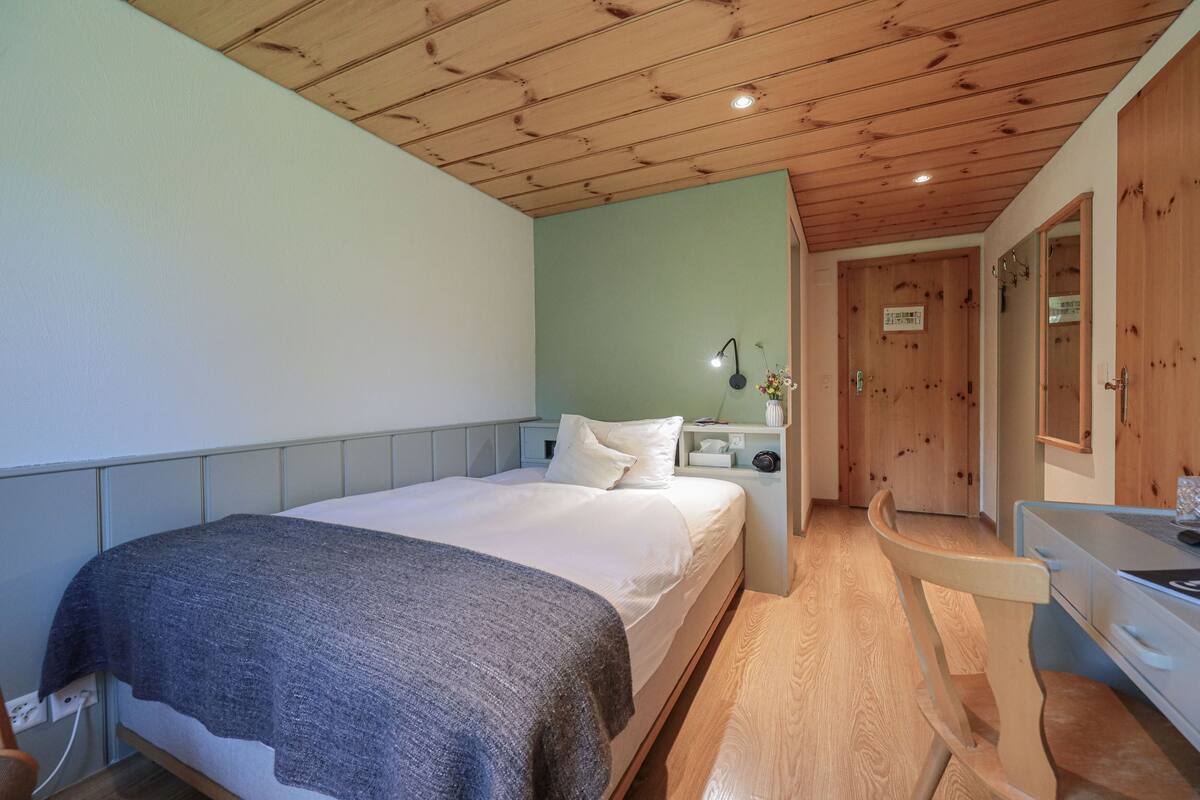 Ein Schlafzimmer mit Bett, Nachttisch, Lampe und Spiegel.