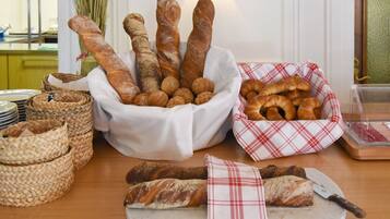 Variedad de panes y pasteles exhibidos sobre una mesa de madera, con cestas y una tabla de cortar.